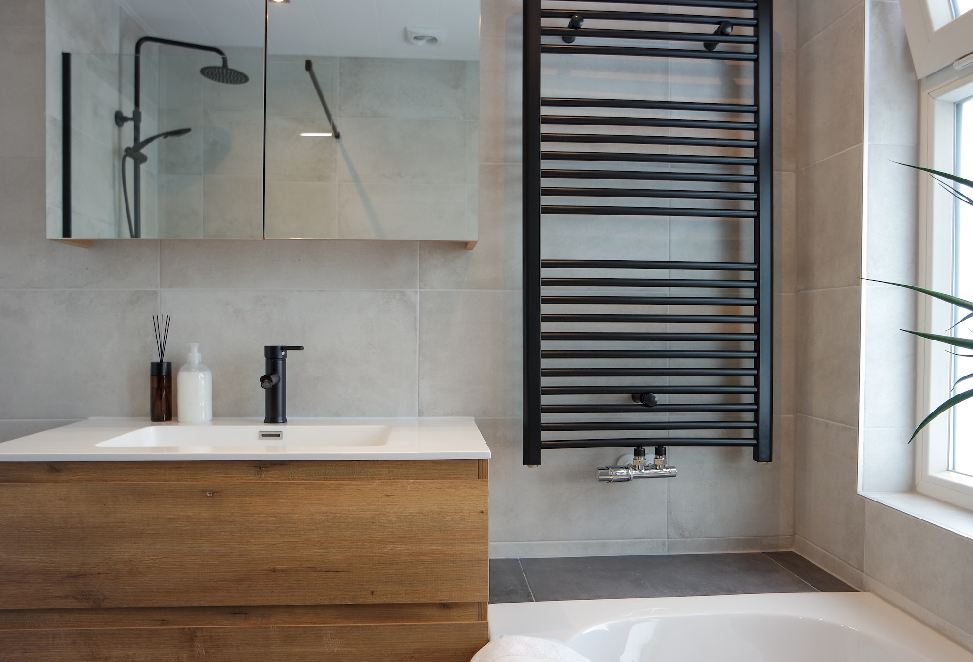 Modern minimalistic bathroom with sink, bath and shower with black details.